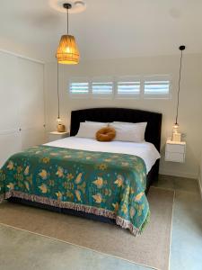 1 dormitorio con 1 cama grande con manta verde en Erowal Bay Guesthouse Jervis Bay, en Erowal Bay