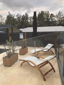 eine Terrasse mit 2 Stühlen, einem Tisch und einem Sonnenschirm in der Unterkunft Erowal Bay Guesthouse Jervis Bay in Erowal Bay