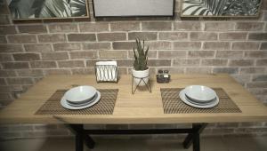 a wooden table with plates and a plant on it at Lujoso depa cerca del consulado. in Ciudad Juárez