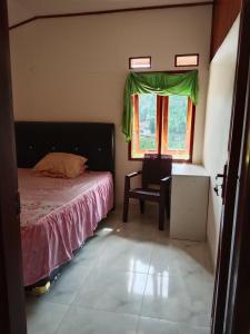 a bedroom with a bed and a chair and a window at Hostel Papa Tia in Rantepao