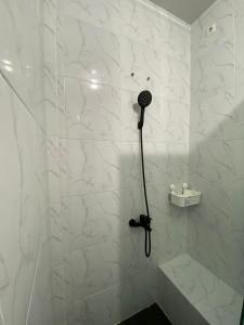 W łazience z białymi marmurowymi ścianami znajduje się prysznic. w obiekcie Villa Shafa Marwa w mieście Bukittinggi