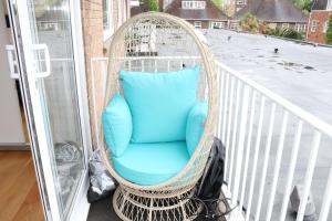 a wicker chair on a balcony with a blue pillow at Garland Lovely Apartment, St John's Wood in London