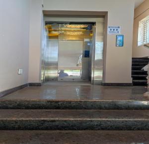 un ascenseur dans un immeuble avec une porte en verre dans l'établissement Shalog Inn Homestay, à Thirumurugan Poondi