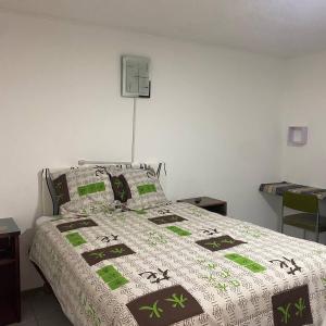 ein Schlafzimmer mit einem Bett mit einer grünen und weißen Decke in der Unterkunft Calu L' Petit Hostel in Quito