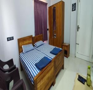 1 dormitorio con cama de madera con rayas azules y blancas en Shalog Inn Homestay en Thirumurugan Poondi