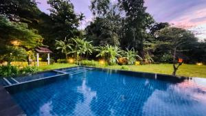 a swimming pool in a garden at night at Fern Resort Mae Hong Son in Mae Hong Son