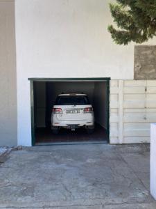 Une voiture blanche est installée à l'intérieur d'un garage. dans l'établissement Just-a-bed - Stone Cottage, à Graaff-Reinet