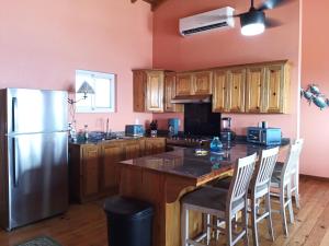 una cocina con nevera de acero inoxidable y armarios de madera en Casa Corazon Striking Beach Home, en Utila