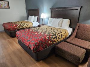 a hotel room with two beds and a chair at Econo Lodge Biltmore in Asheville +4 photos