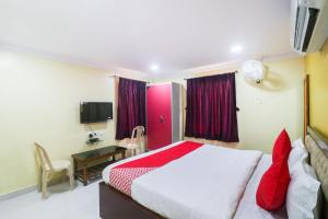KhandagiriにあるOYO Devi Residencyのベッドルーム(ベッド1台、デスク、テレビ付)