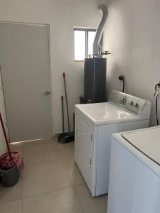 eine weiße Waschküche mit einer Waschmaschine und einem Fenster in der Unterkunft Casa Arcana (3 minutos del consulado) in Ciudad Juárez