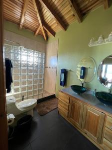 ein Badezimmer mit einem Waschbecken, einem WC und einem Spiegel in der Unterkunft Casa Corazon Striking Beach Home in Utila