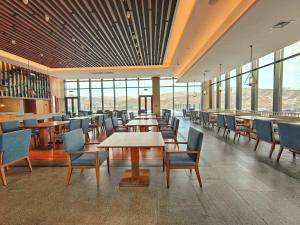 a dining room with tables and chairs and windows at Oakwood Suites Chongli in Chongli