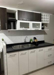 a kitchen with white cabinets and a sink at Departamento Lucas in Trujillo