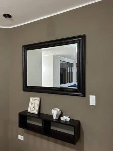 a mirror on a wall with a black shelf at Departamento Lucas in Trujillo