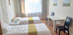Cette chambre comprend deux lits, une table et un bureau. dans l'établissement Gandan Terrace Guesthouse, à Oulan-Bator