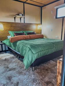1 dormitorio con 1 cama grande y edredón verde en TINY EL ZAPATO, en Suesca