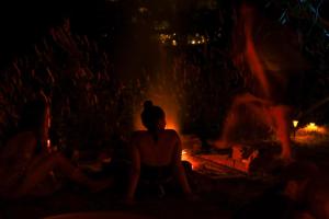 a woman sitting in front of a fire at night at Atlas Valley in Pai