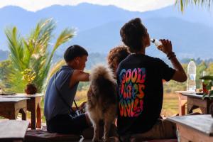 un grupo de personas sentadas en mesas con un perro en Atlas Valley en Pai