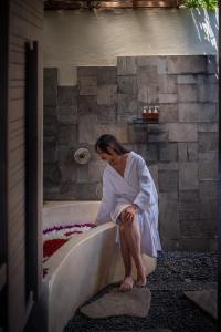 a woman sitting on a bathtub in a room at Ubud Padi Villas in Ubud
