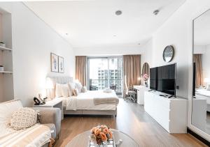 a white bedroom with a bed and a tv at 5-Star Studio at The Address Marina, Mall Access in Dubai