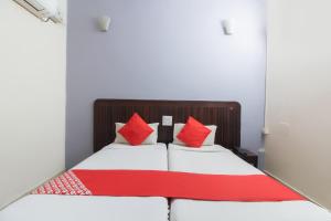 a bedroom with a bed with red and white pillows at OYO Hotel Regal Near Paradise Circle in Secunderabad