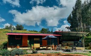 una casa con techo de hierba, mesa y sombrilla en TINY EL ZAPATO, en Suesca