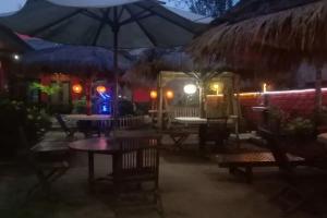 ein Restaurant mit Tischen und Stühlen und einem Sonnenschirm in der Unterkunft Puri Karimunjawa RedPartner in Karimunjawa