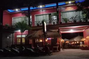 ein Restaurant mit einem Strohschirm und Stühlen in der Nacht in der Unterkunft Puri Karimunjawa RedPartner in Karimunjawa