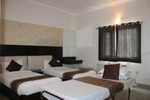 a hotel room with three beds and a window at Hotel Mani Ram Palace Agra in Agra