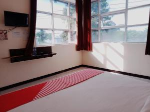 a bedroom with a red and white bed with windows at Rahayu Residence Syariah Kediri in Kediri