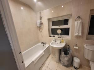 y baño con lavamanos, bañera y lavamanos. en Garland Modern House With Parking & Garden, en Borehamwood