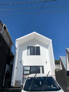 a white car parked in front of a white house at Village Homestay Dieng Syariah in Dieng