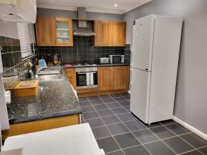 een keuken met een witte koelkast en houten kasten bij Garland Modern House With Parking & Garden in Borehamwood