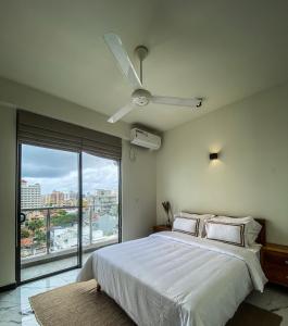 sypialnia z białym łóżkiem i wentylatorem sufitowym w obiekcie Marine Breeze Residencies w Kolombo