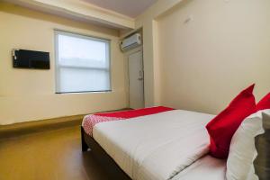 a bedroom with a bed with red pillows and a window at Alpine glow Zenith in Hyderabad