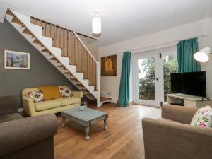 a living room with a couch and a staircase at Woodlands Cottage in Leominster