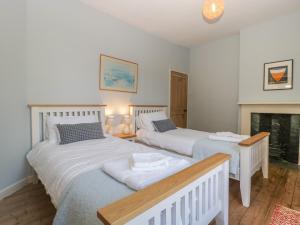 two beds in a room with a fireplace at Woodlands Cottage in Leominster