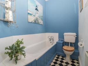a blue bathroom with a toilet and a tub at Woodlands Cottage in Leominster +35 photos