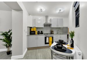 a kitchen with white cabinets and a table with dishes on it at Explorer’s Studio - Comfort, Peace, Convenience in London