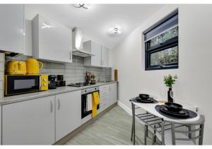 a kitchen with white cabinets and a table with chairs at Explorer’s Studio - Comfort, Peace, Convenience in London