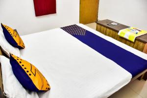 a bed with yellow and blue pillows in a room at SPOT ON City Tower Inn in Jāmul