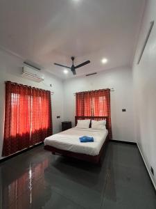 1 dormitorio con 1 cama y 2 ventanas con cortinas rojas en MATHER RAJAGIRI FURNISHED APARTMENTS en Alwaye