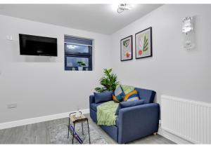 a living room with a blue couch and a tv at Green Haven Sleeps Two in London