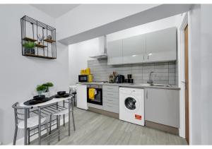 a white kitchen with a washing machine and a table at Green Haven Sleeps Two in London