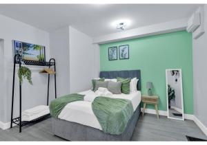 a bedroom with a large bed with green walls at Green Haven Sleeps Two in London