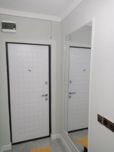 Łazienka z 2 białymi drzwiami i lustrem w obiekcie Orda w Kyzyłordzie