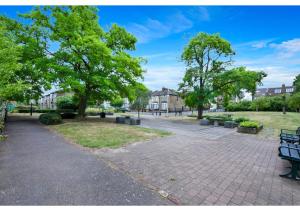 un parco con panchina e alberi e case di Green Haven Sleeps Two a Londra