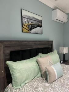 1 cama con almohadas verdes y una foto en la pared en Alexia's Stay, en Portmore