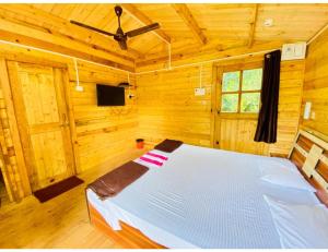 Cette chambre en bois comprend un lit blanc. dans l'établissement Mermaid Resort, Arambol, Goa, à Arambol